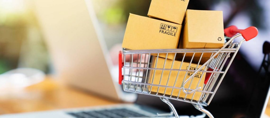Package boxes in cart with laptop computer for online shopping concept